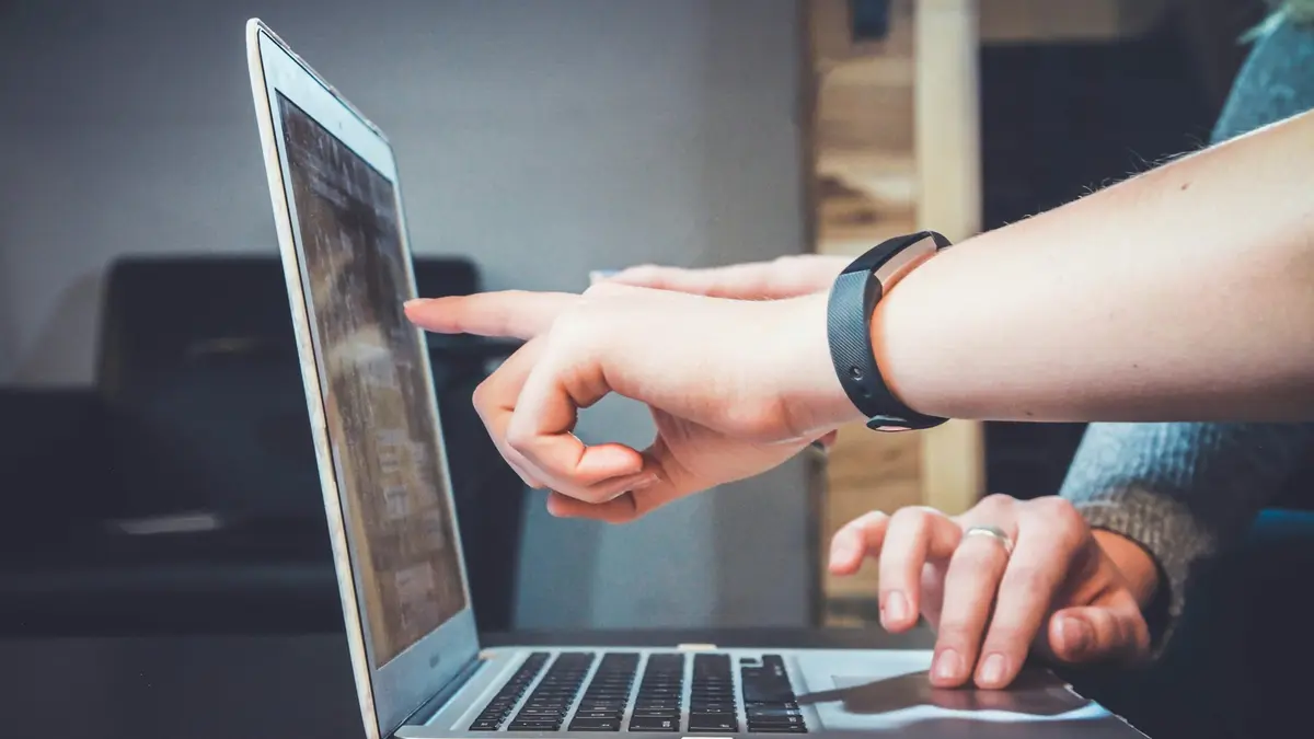 Two people looking at a laptop screen together, one of them pointing at it